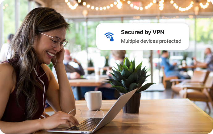 カフェで女性が笑いながらノートパソコンの画面を見ている